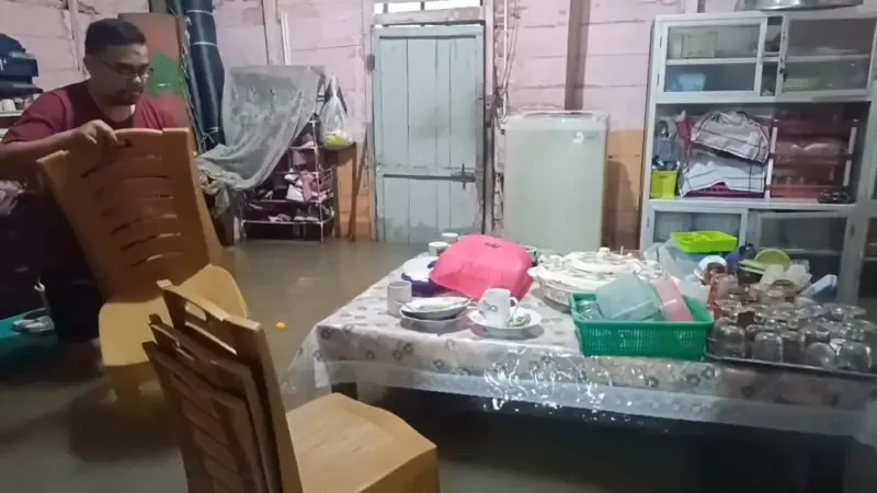 Misrina dan suami membersihkan rumahnya yang diserang banjir pada Minggu (30/03).